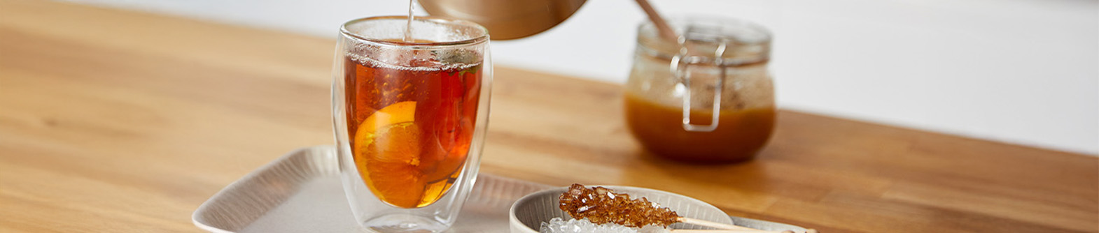 Teeglas mit schwarzem Tee und Zitronenscheibe