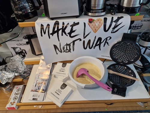 Aufgeklapptes Waffeleisen mit einer Schüssel Teig daneben