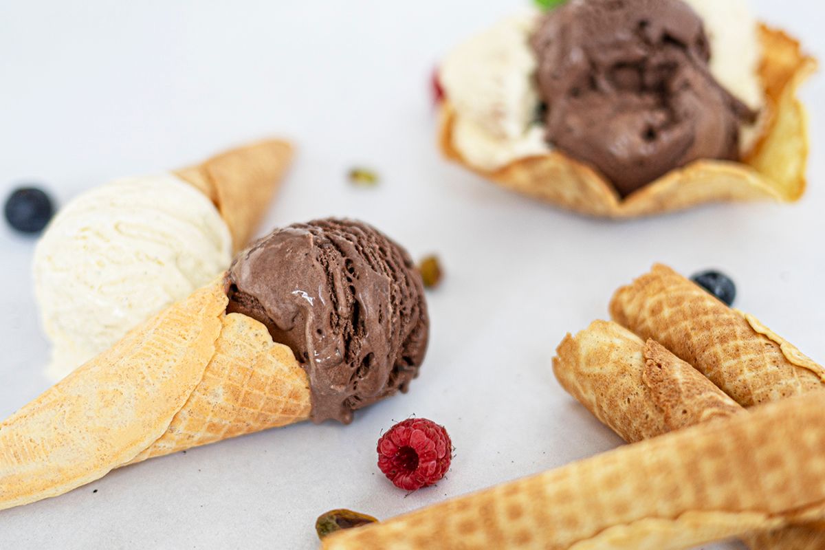 Das Bild zeigt Waffelhörnchen mit Eis sowie Blau- und Himbeeren