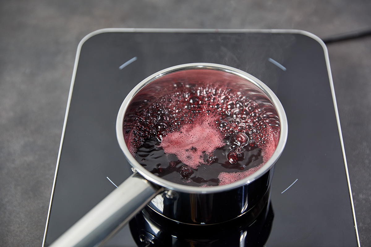 Das Bild zeigt aufgekochten Kirschsaft auf einer Induktionsplatte.