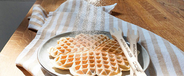 Das Bild zeigt eine Herzwaffel die mit Puderzucker bestreut wird.